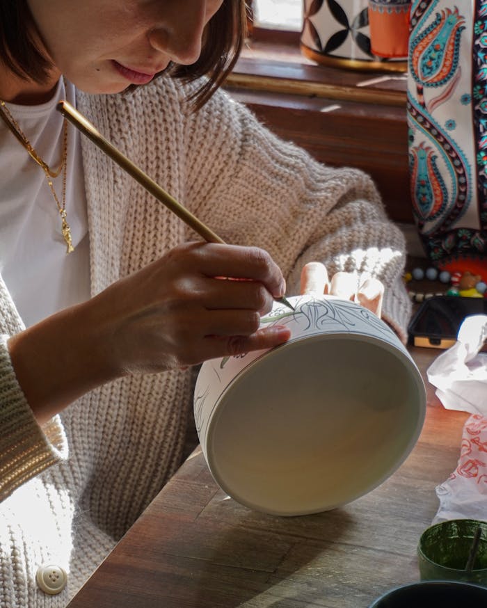 services-03 An artisan meticulously painting a ceramic bowl in a sunlit Bursa studio, Türkiye.
